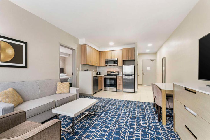 living room opening into kitchen area with countertops, shelves, oven and a fridge