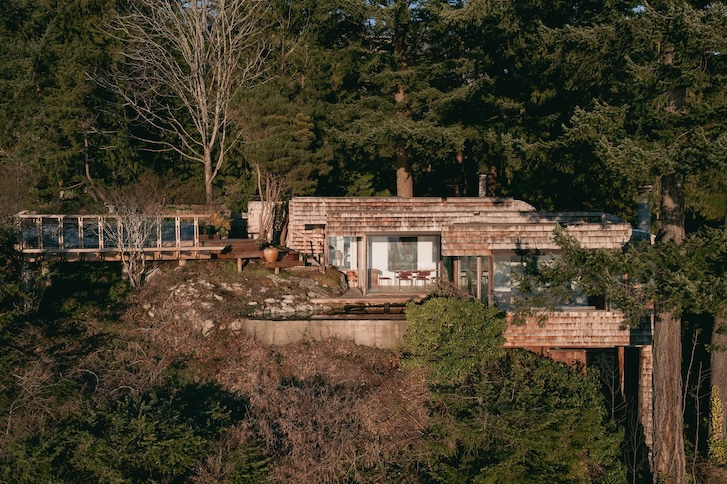 waterfront home nestled and has multiple levels that cascade down a rock cliff