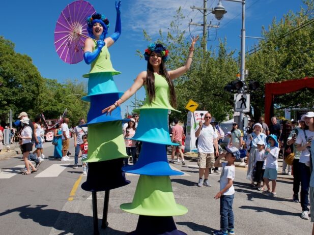 2 stilt-walking ladies wearing colorful styled layered long dresses