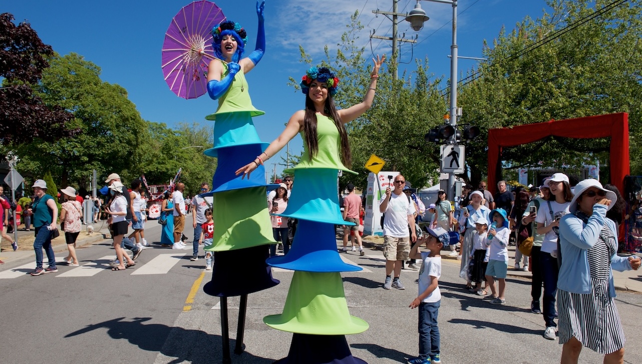 2 stilt-walking ladies wearing colorful styled layered long dresses