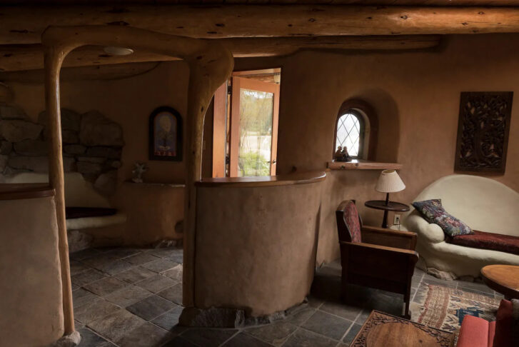 inside of a copper-coloured cob, with the floors dressed in stone tiles and rustic wooden beams across the ceiling