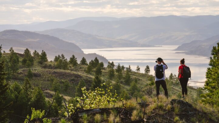 a man and woman up on a mountain hike and taking a picture of the skyview