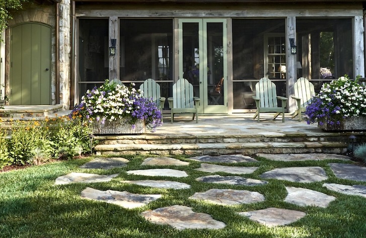 a stone pathway at a backyard with sitting chairs and plants around