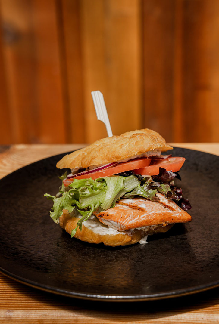 a salmon burger on a black plate 