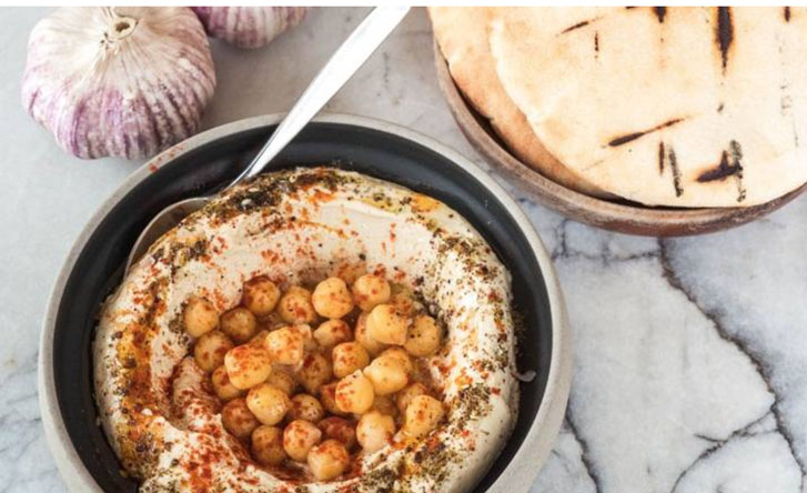 chickpeas in a bowl of hummus and a plate of pita bread