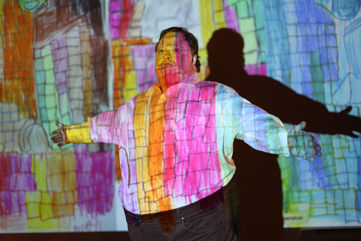 man standing on a colorful lit theatre stage