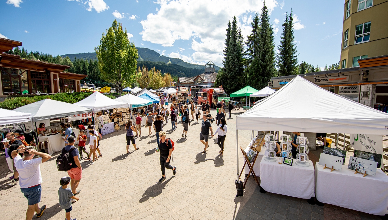 local artisans and crafts market with various people walking about with white tents of arts and crafts stands