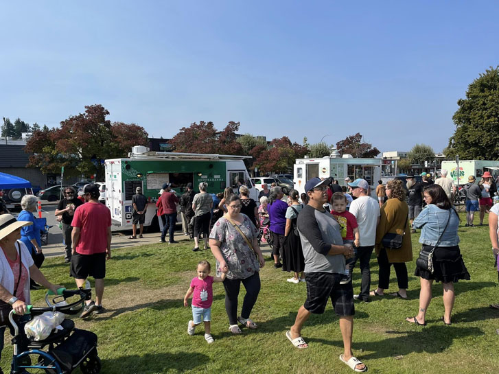 food trucks with groups of people walking towards the trucks and around the field