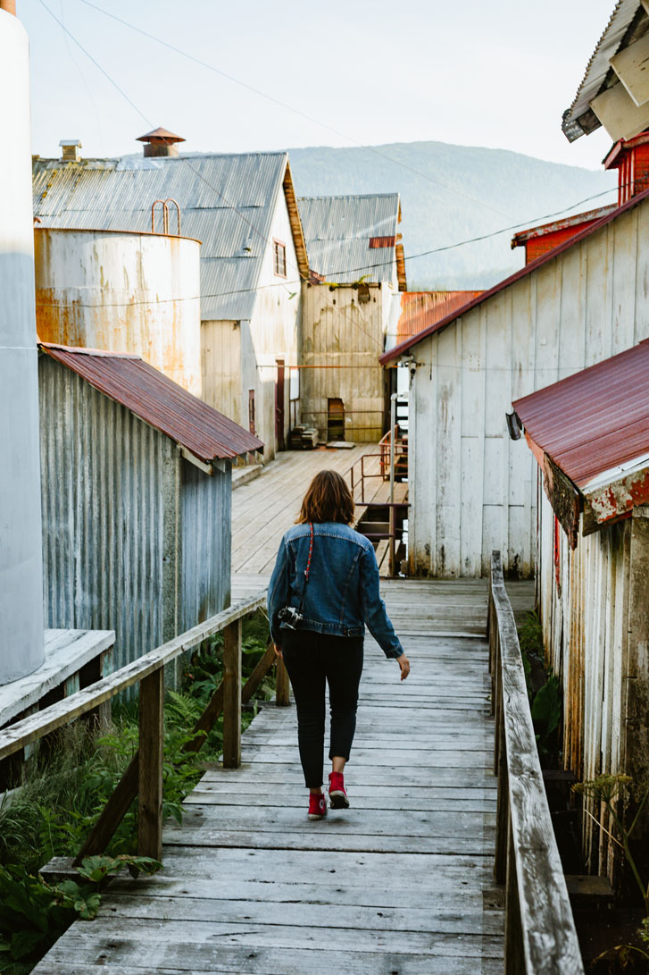 lady walking down a boardwalk with old zinc houses around the sites