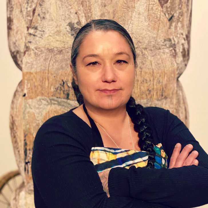 a chef woman standing in front of an art wall