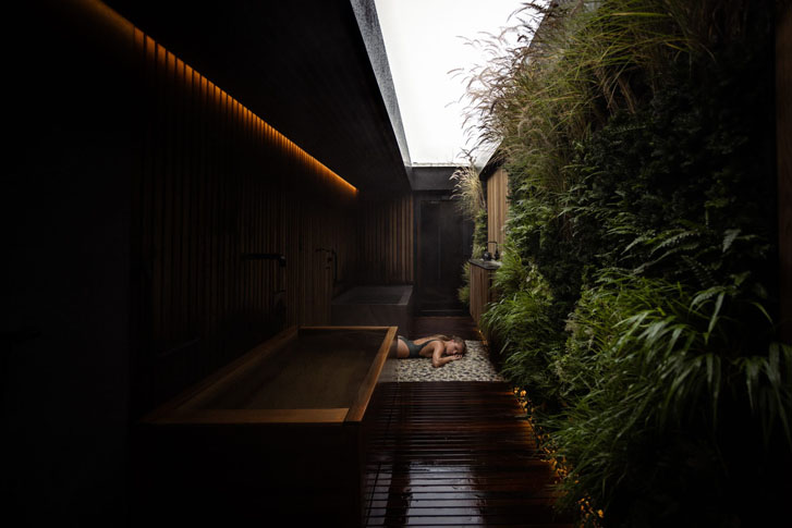 woman in bathing suit relaxing on the floor at a dark calm spa