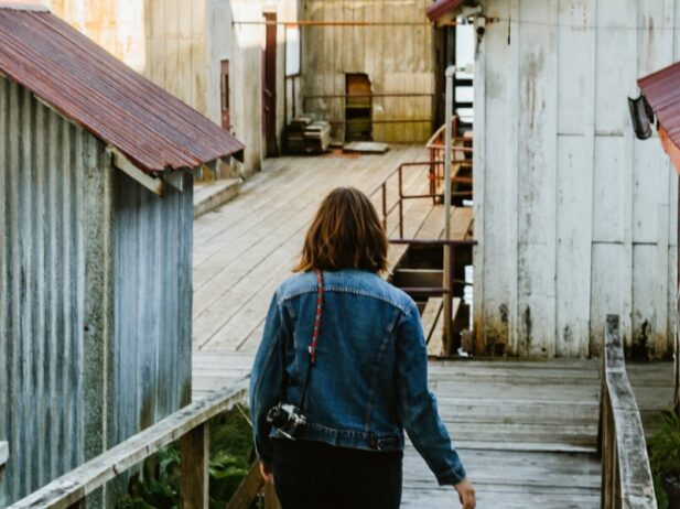 lady walking down a boardwalk with old zinc houses around