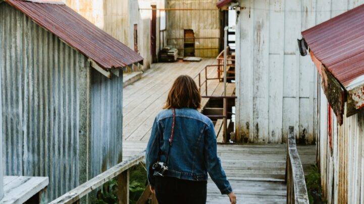 lady walking down a boardwalk with old zinc houses around