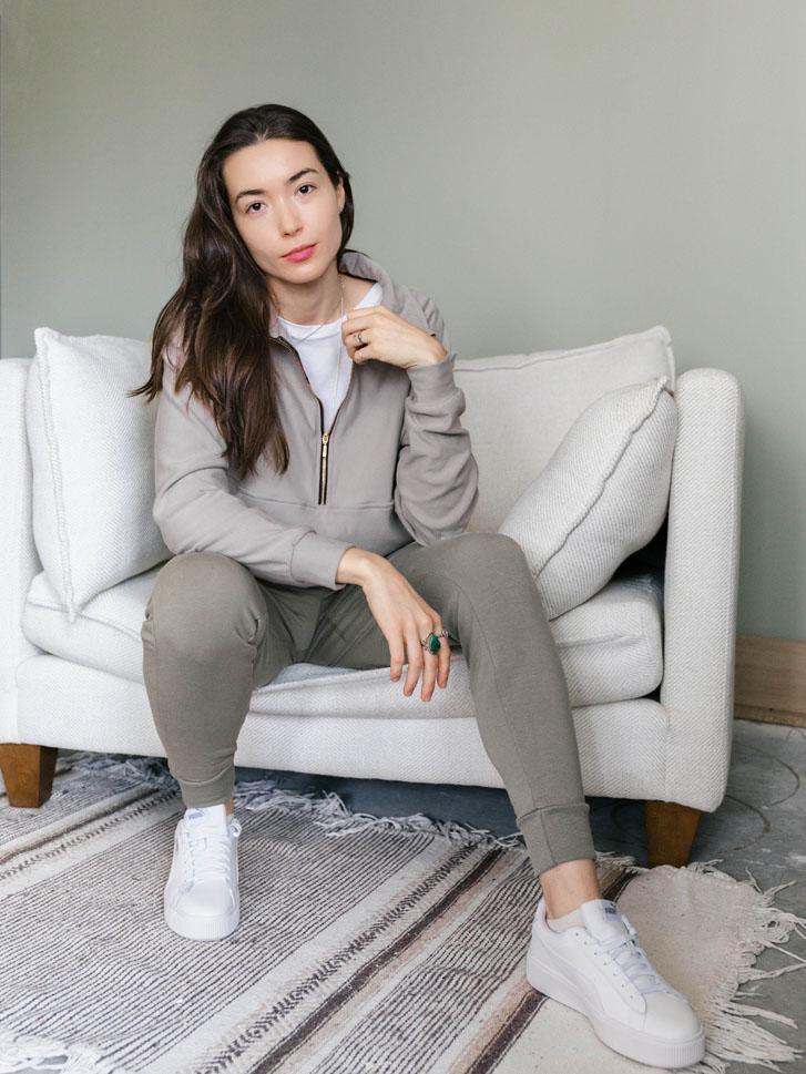 woman sitting on a couch in a sweatshirt by a brand