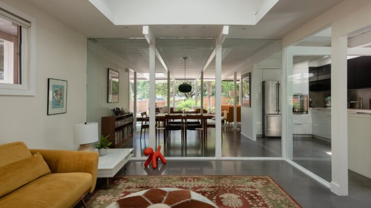 a dream home living room with a yellow couch and glass doors opening into the dining room