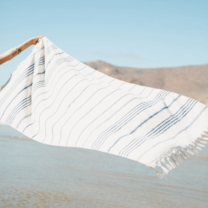 towel from Droplet Home Goods being held in the air at the beach