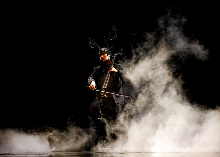 man in black custom playing the cello at a Cirque Du Soleil show