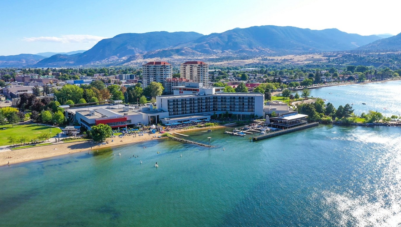 aerial view of a massive resort buildings behind a huge lake with a beach area