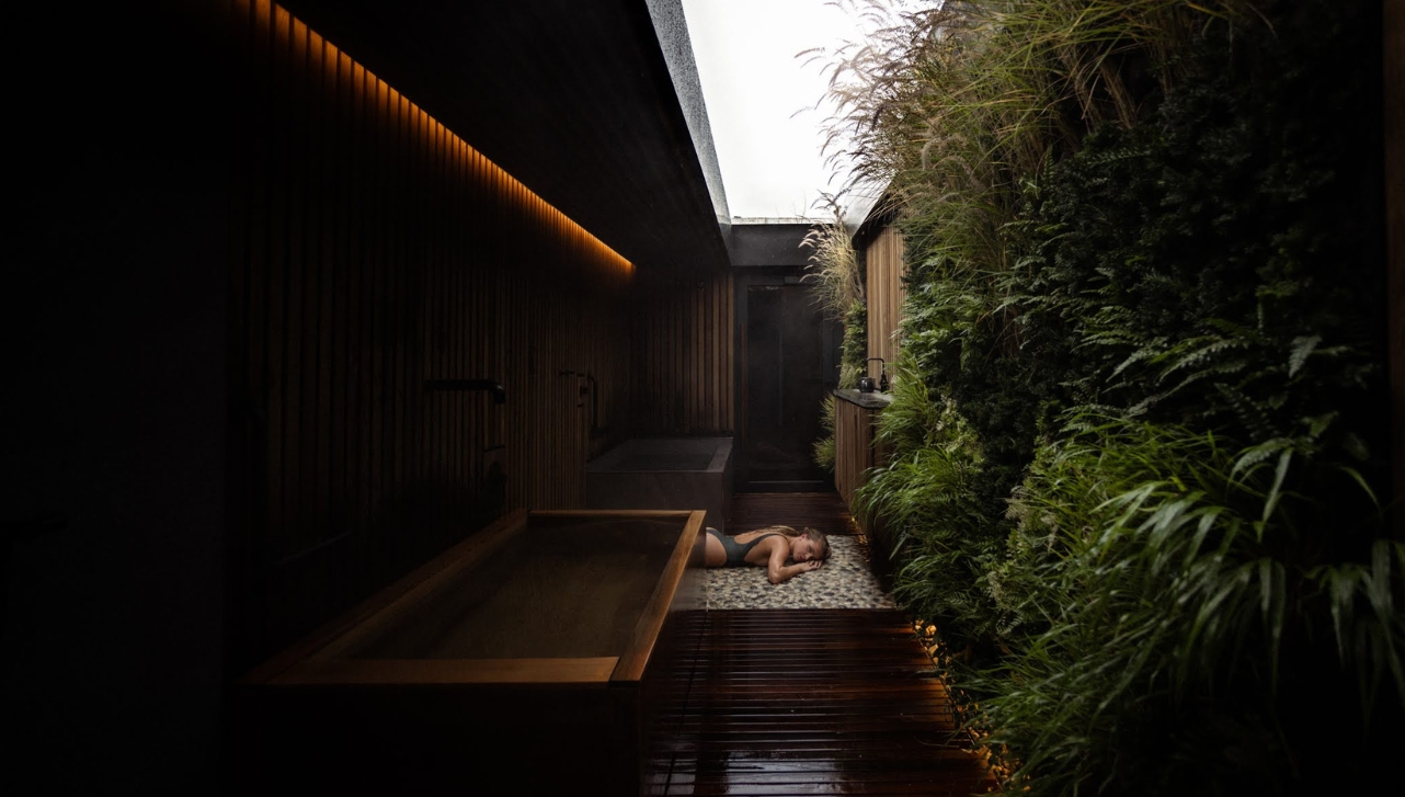 woman in bathing suit relaxing on the floor at a dark calm spa