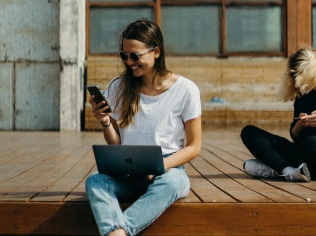 woman sitting on a deck with her laptop and phone