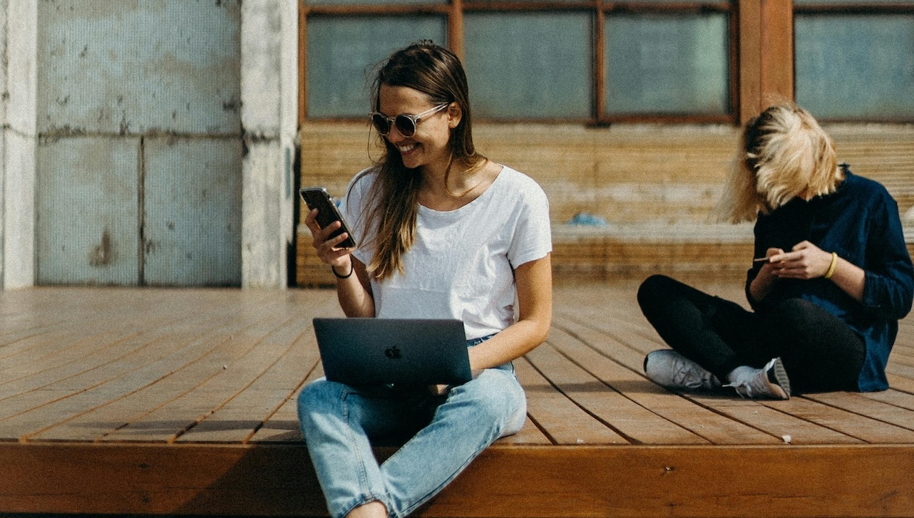 woman sitting on a deck with her laptop and phone