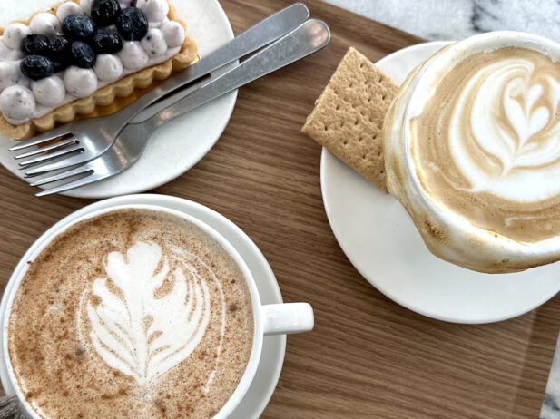 Table with cups of coffee, a cracker and a sweet snack