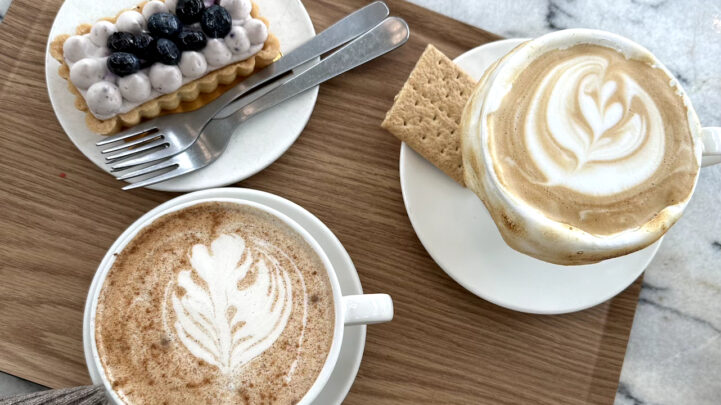 Table with cups of coffee, a cracker and a sweet snack