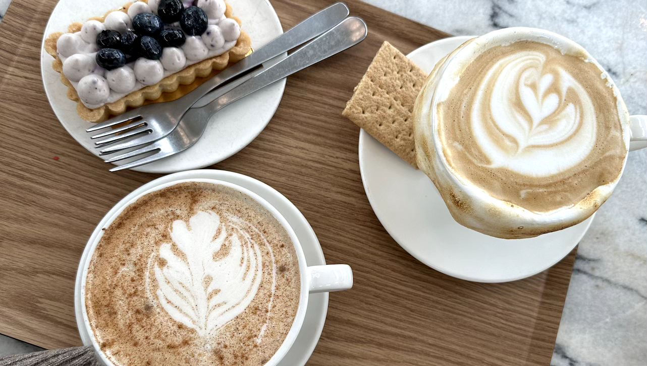 Table with cups of coffee, a cracker and a sweet snack