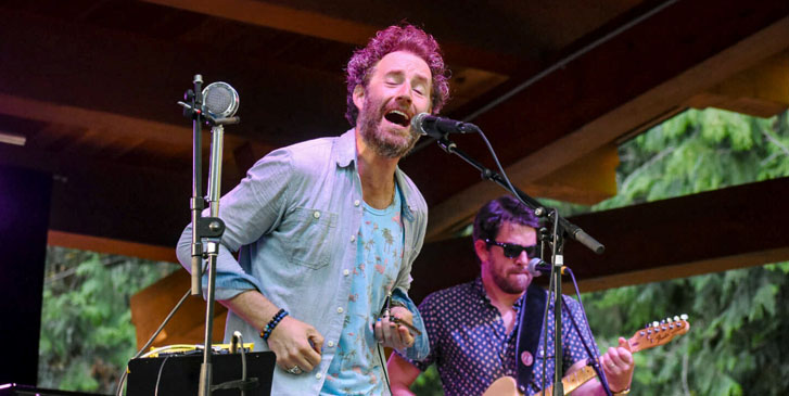 a man singing to a standing microphone and a guitarist playing the guitar