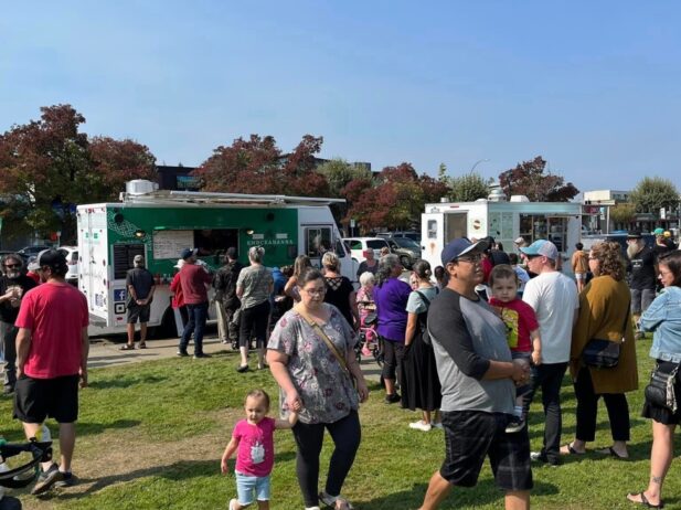 food trucks with groups of people walking towards the trucks and around the field