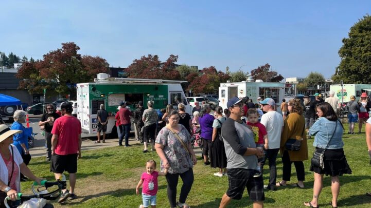 food trucks with groups of people walking towards the trucks and around the field