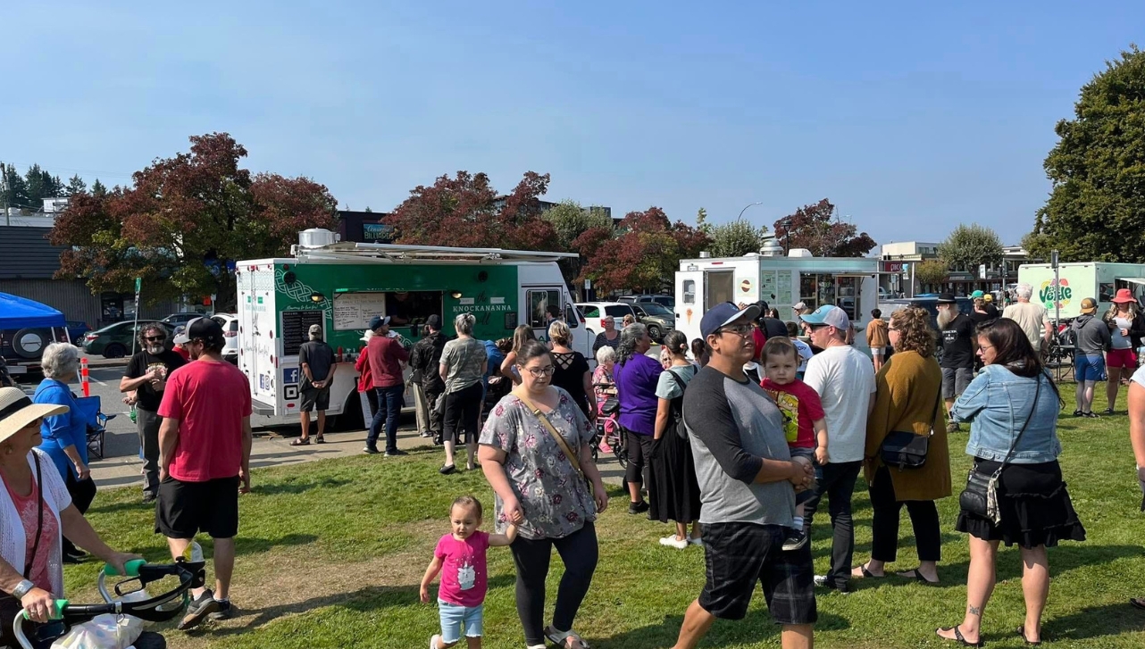 food trucks with groups of people walking towards the trucks and around the field