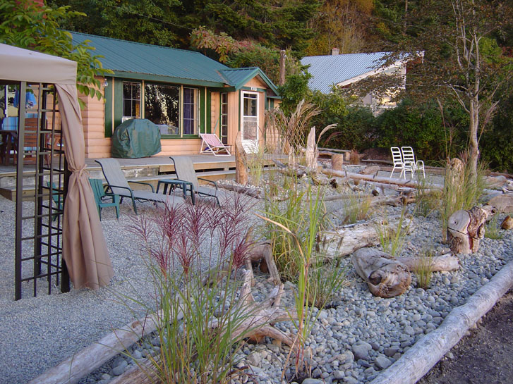 a cottage-like house with woods, chairs and a canopy in front of the house