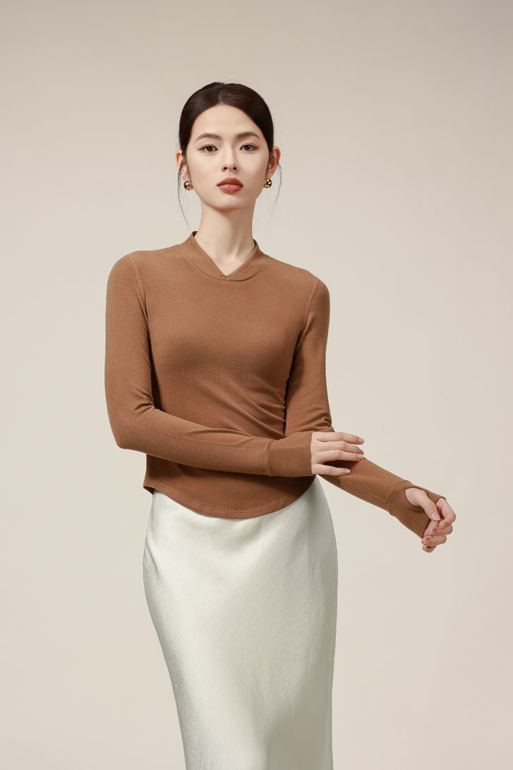 asian lady wearing a fashion brown longsleeve v-neck and a long silk skirt with her hands elegantly bent to a side