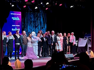 group of performers standing together on a theatre stage 