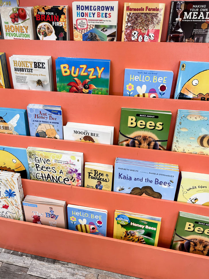 a layered shelve with rows of children bee books and a few adult bee books