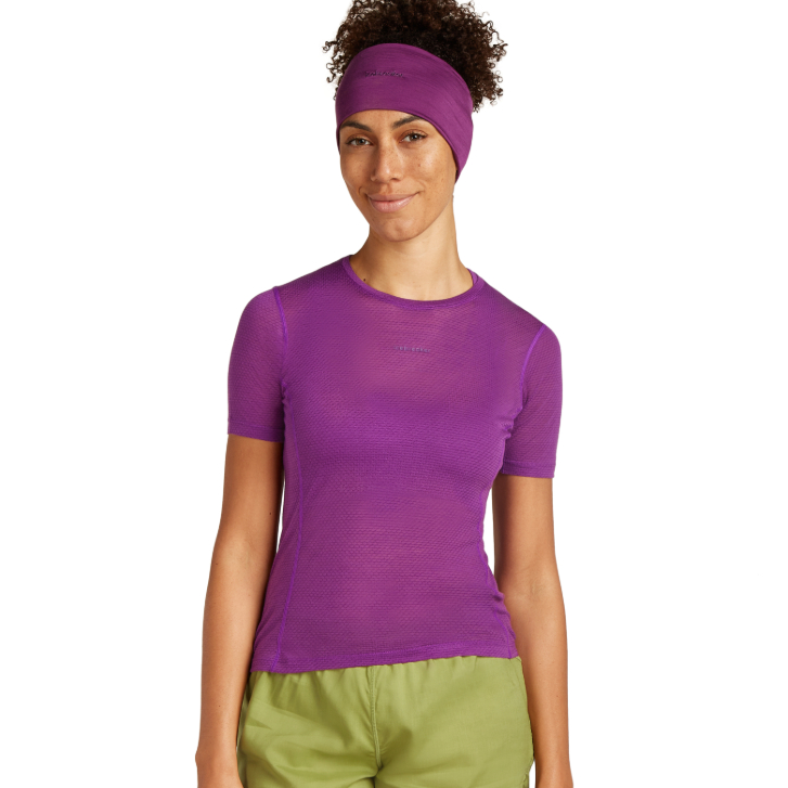 woman posing in a purple athletic shirt and green shorts