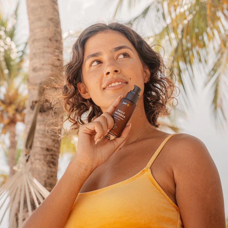 Woman in yellow bikini holding Just Sun product