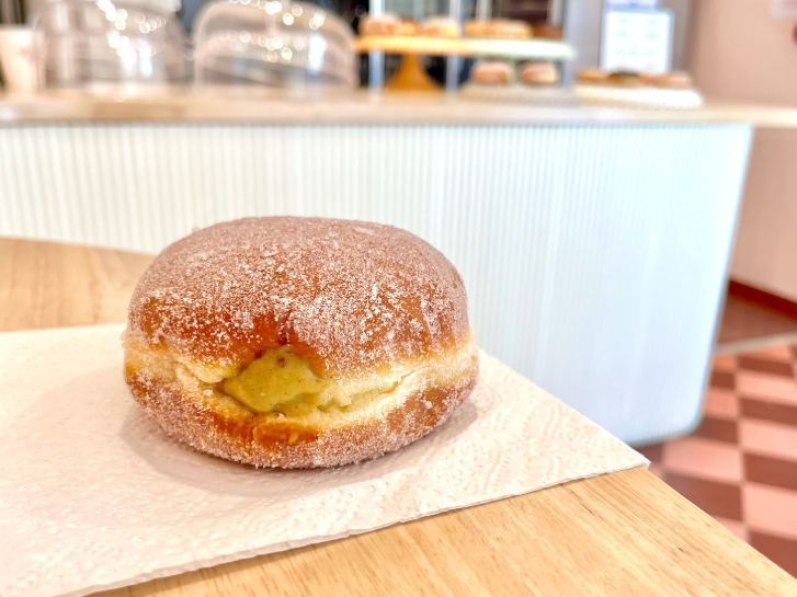 a cream filled sugar donut on a wooden table 