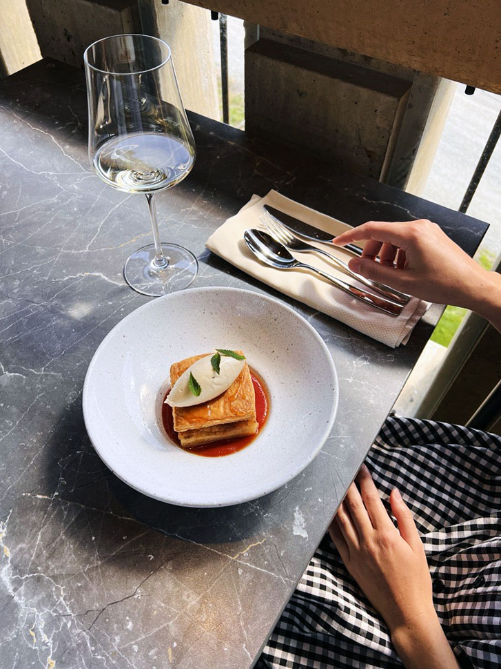 Mission Hill Estate's apple tart tatin recipe on a plate with a lady's hand picking up the knife beside the plate