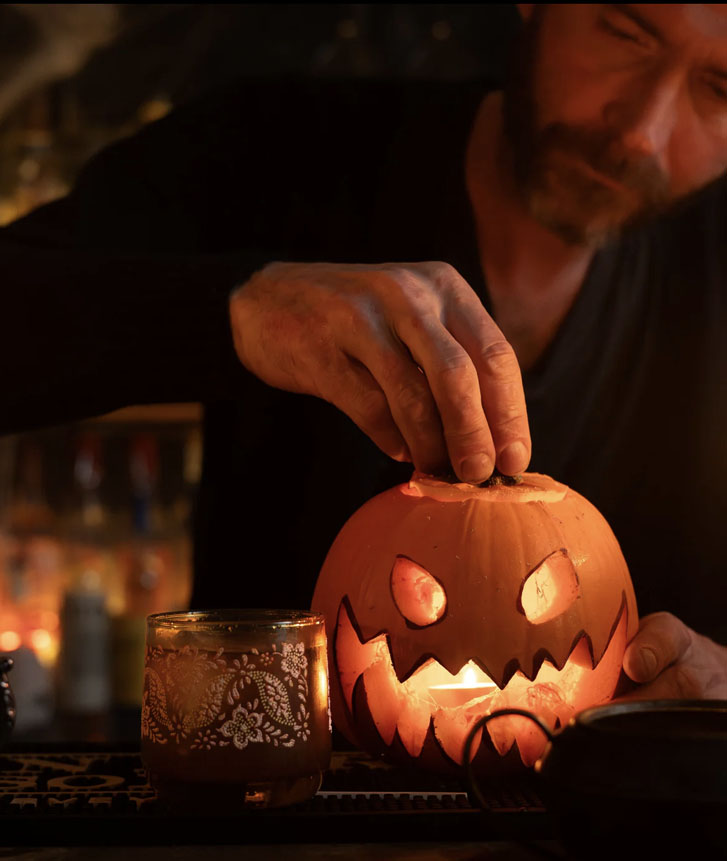 man closing a pumpkin-made lamp