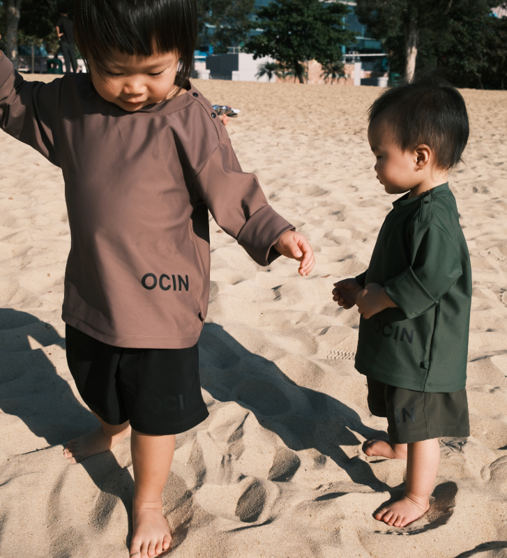 two kids wearing OCIN apparel walking in the sand