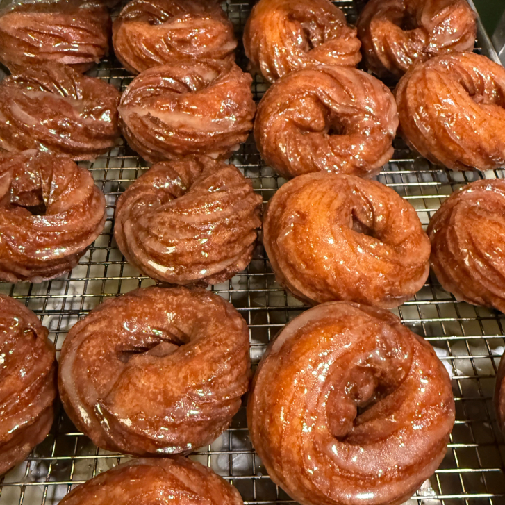 rows of glazed donuts on a drying tray