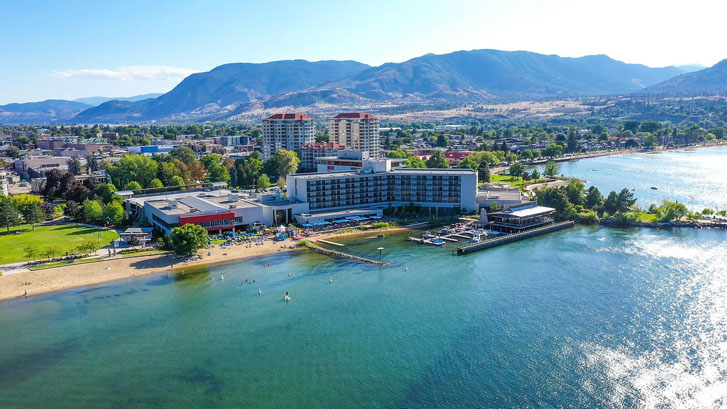 aerial view of a massive resort buildings behind a huge lake with a beach area