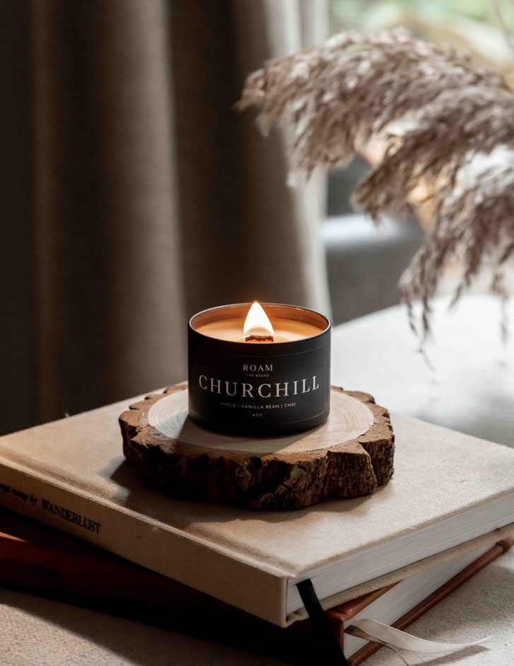 lit scent candle placed on a wooden surface on a stack of books on a table