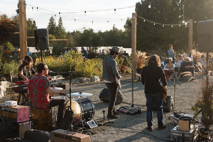 2 guitarists, a drummer and a pianist with their instruments at an outdoor event