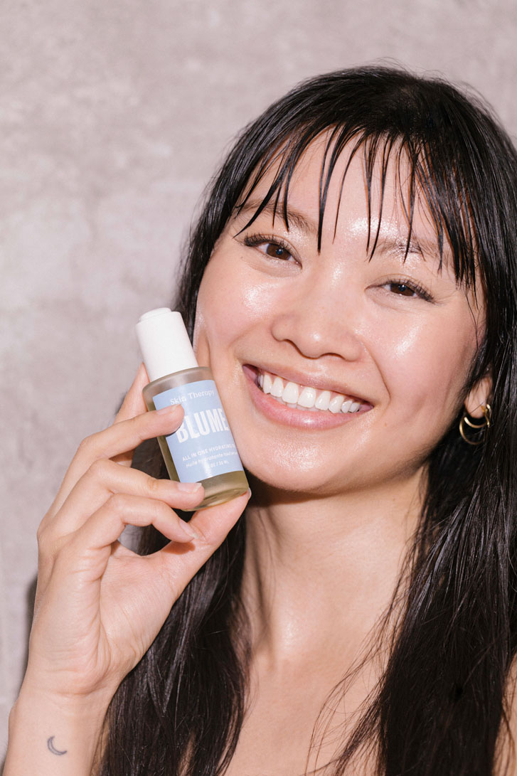 asian girl holding a product titled "Blume" next to her face's skin while smiling