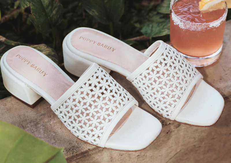 The Paloma Heel from Poppy Barley in white next to a drink