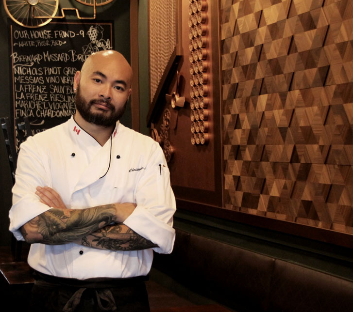 asian chef and restaurateur man standing in front of his menu board with his arms crossed