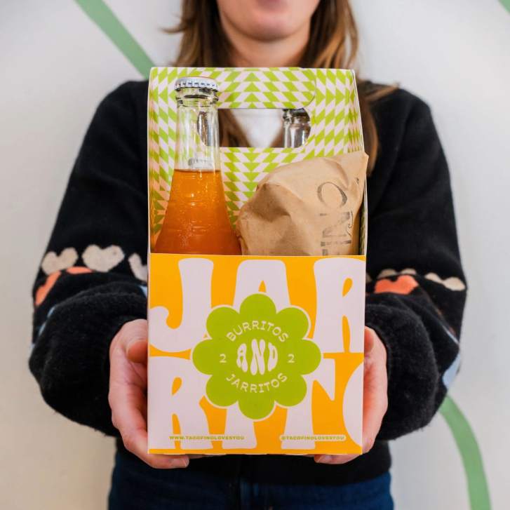 person holding a box of Tacofino burritos and jarritos